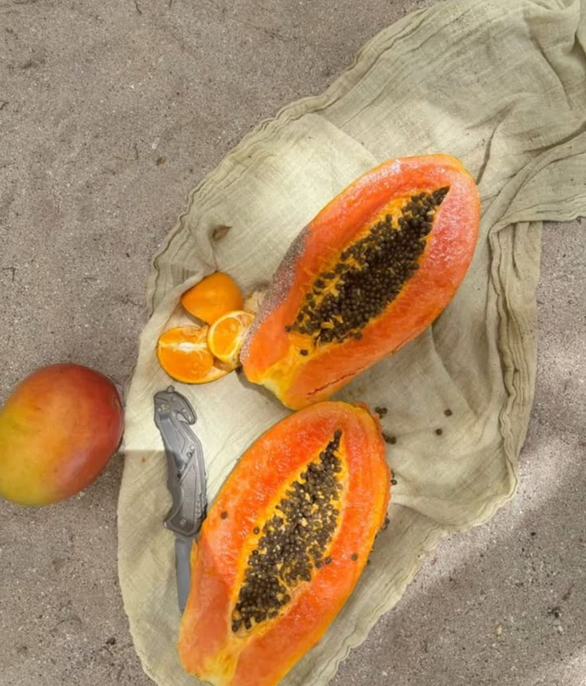 Close-up of a woman biting into a wedge of fresh papaya, seeds still visible in the fruit.