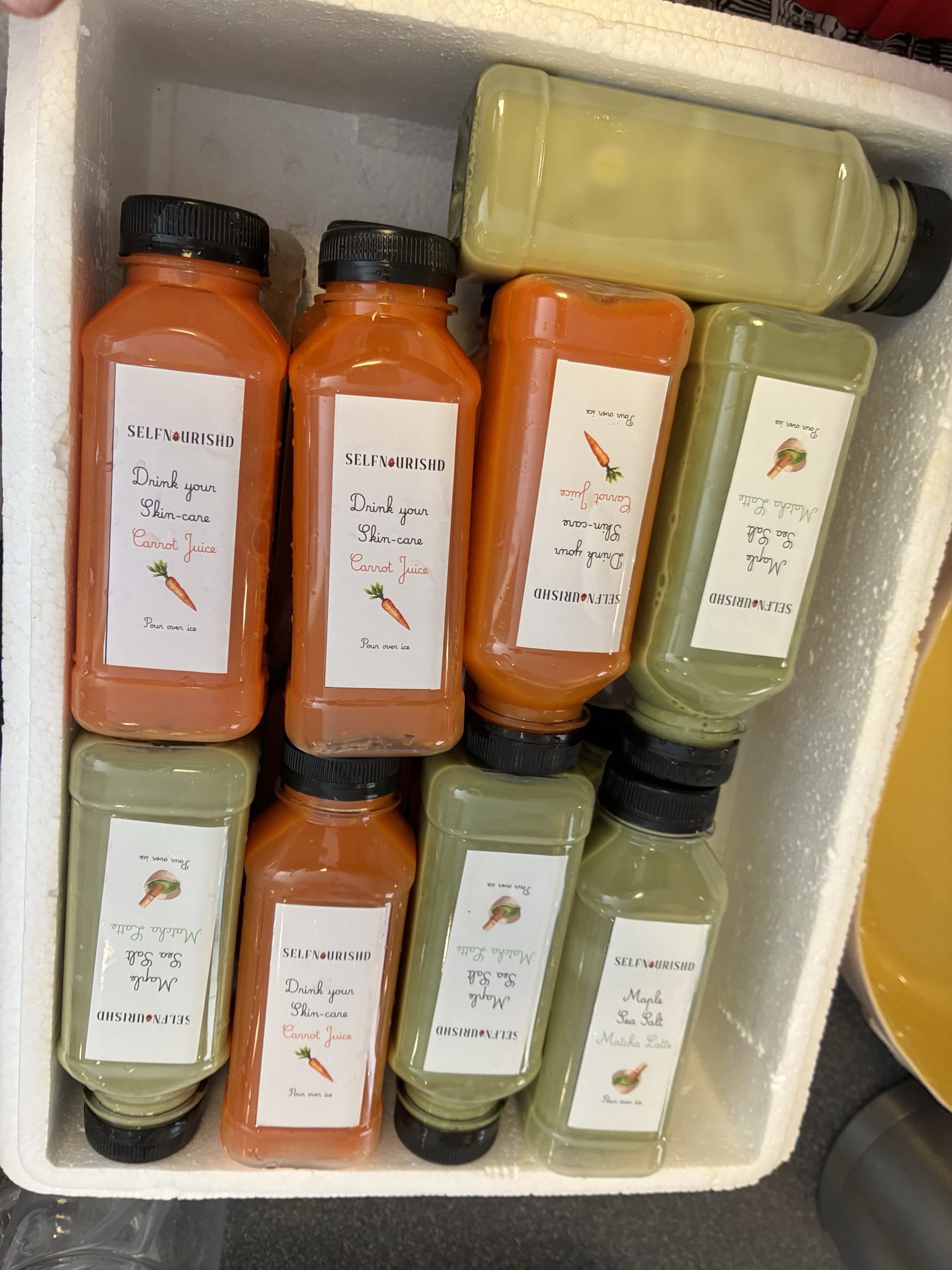 Bottles of matcha latte and carrot juice packed side by side