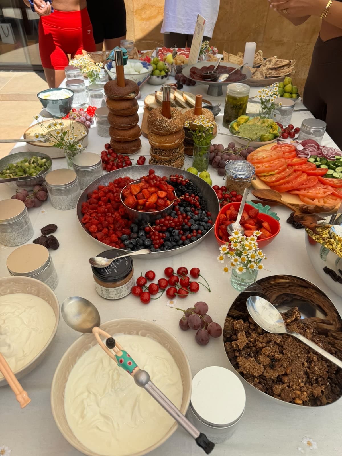 Large bowls of yoghurt and granola at the end of the table with kiwi, cherries and dates