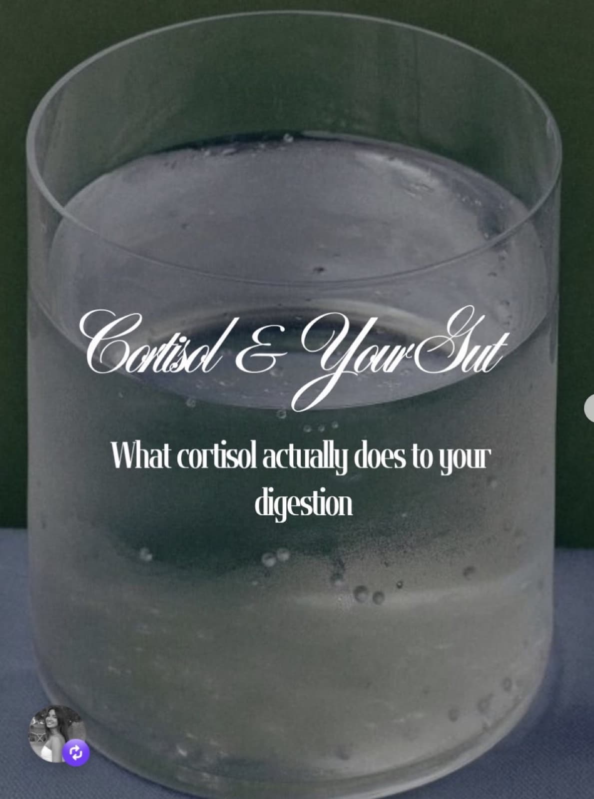 A close-up glass of water with rising bubbles, against a dark green background